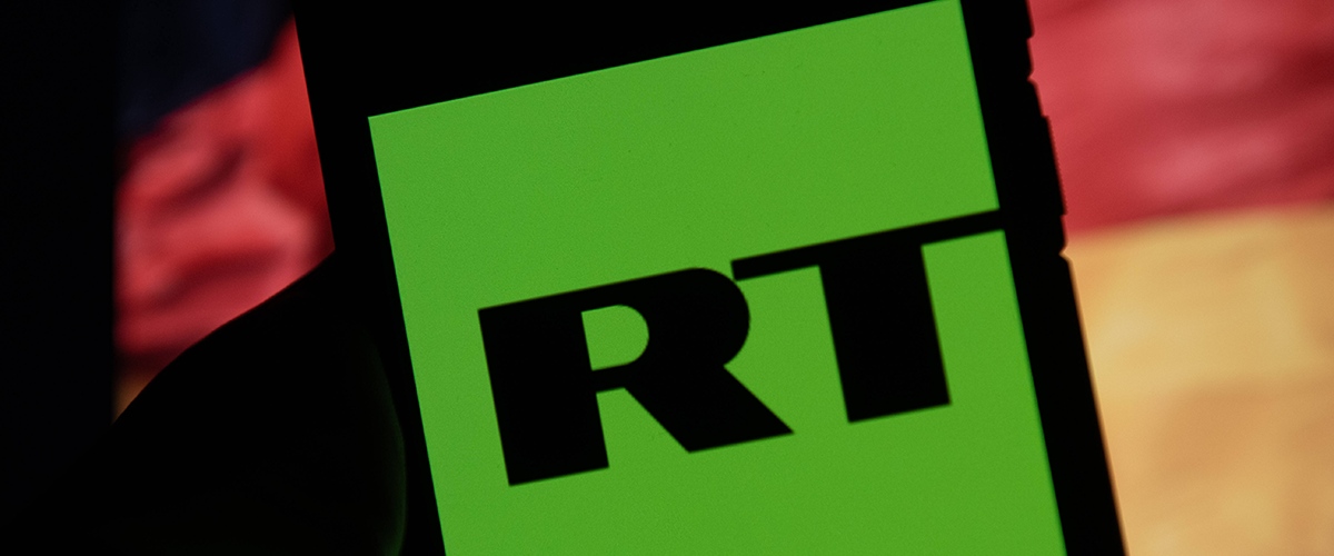 Das Logo von RT auf einem Smartphonebildschirm vor einer deutschen Flagge